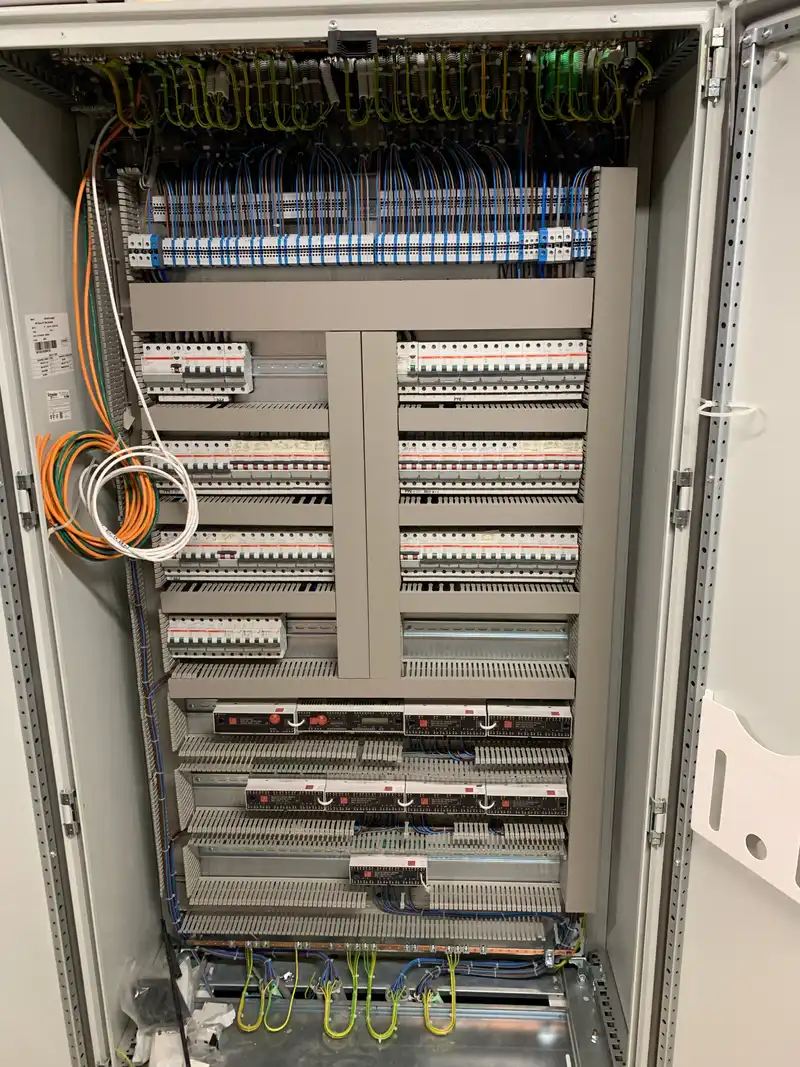 Open verdeelkast met rijen automaten en differentieelschakelaars, genummerde klemmenstroken, een aardingskam en netjes geleide kabelbundels.