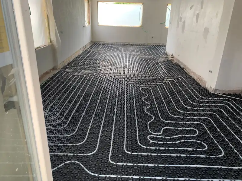Boucles de chauffage par le sol sur toute la surface d’une pièce, fenêtre bandeau à l’arrière.