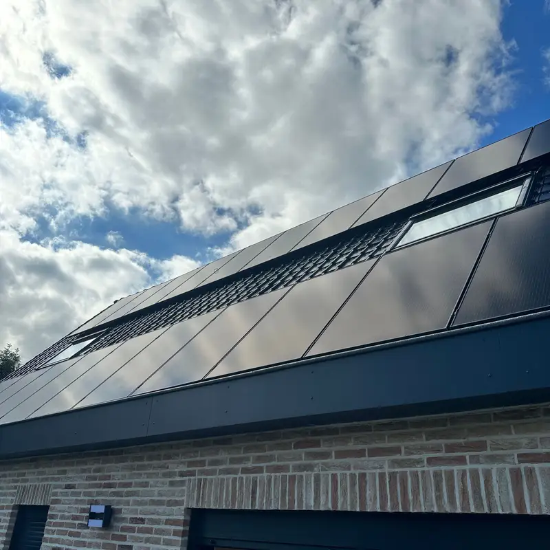 Het nieuwe dak met zonnepanelen en dakvlakvensters, boven de gemetselde gevel.